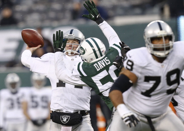 EAST RUTHERFORD, NJ - DECEMBER 8: Matt McGloin #14 of the Oakland Raiders looks to pass in front of DeMario Davis #56 of the New York Jets during their game at MetLife Stadium on December 8, 2013 in East Rutherford, New Jersey. (Photo by Jeff Zelevansky/Getty Images)