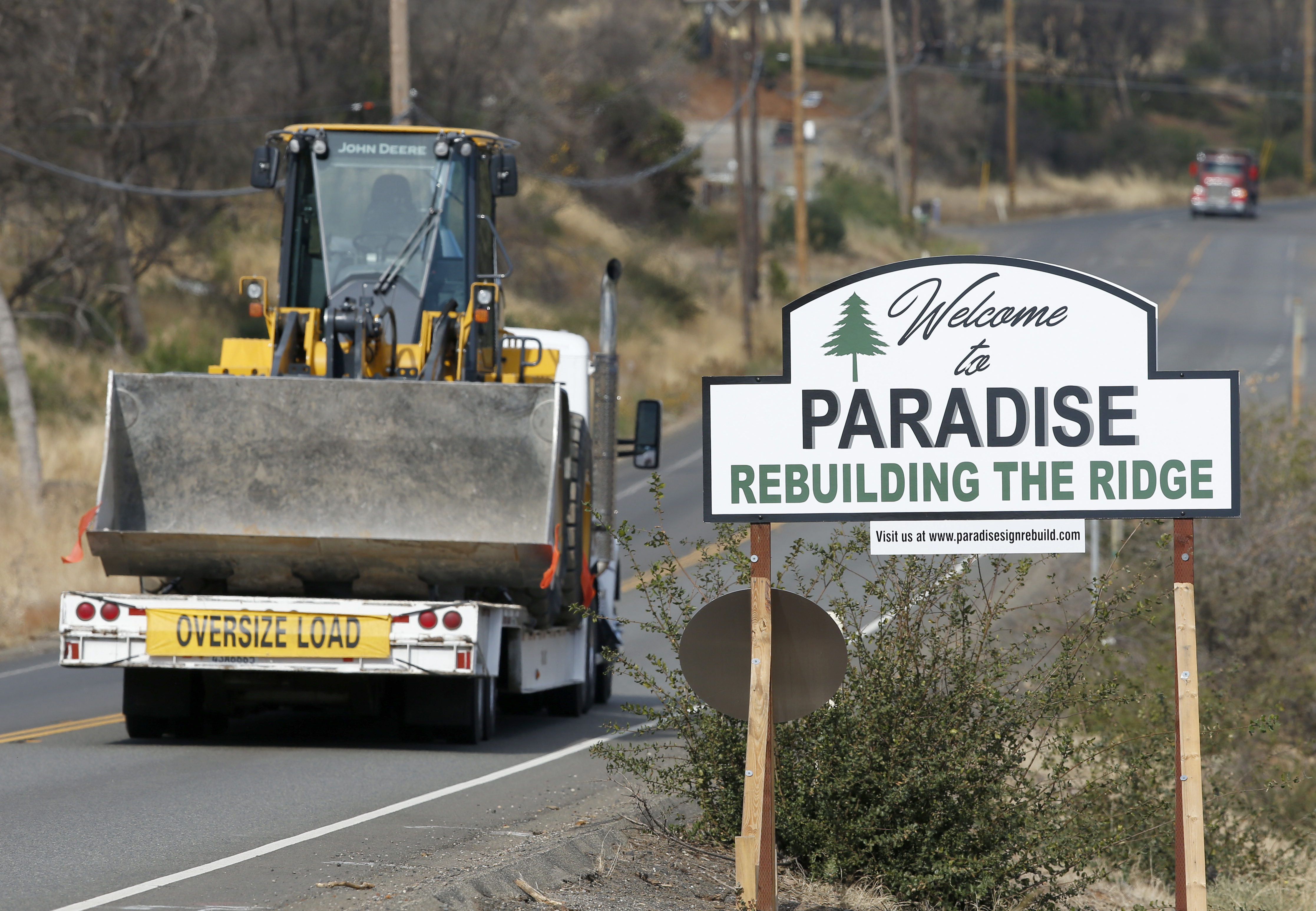 Vehicles pass a sign welcoming people to Paradise, Calif., Tuesday Nov. 5, 2019. The sign also displays the slogan, 