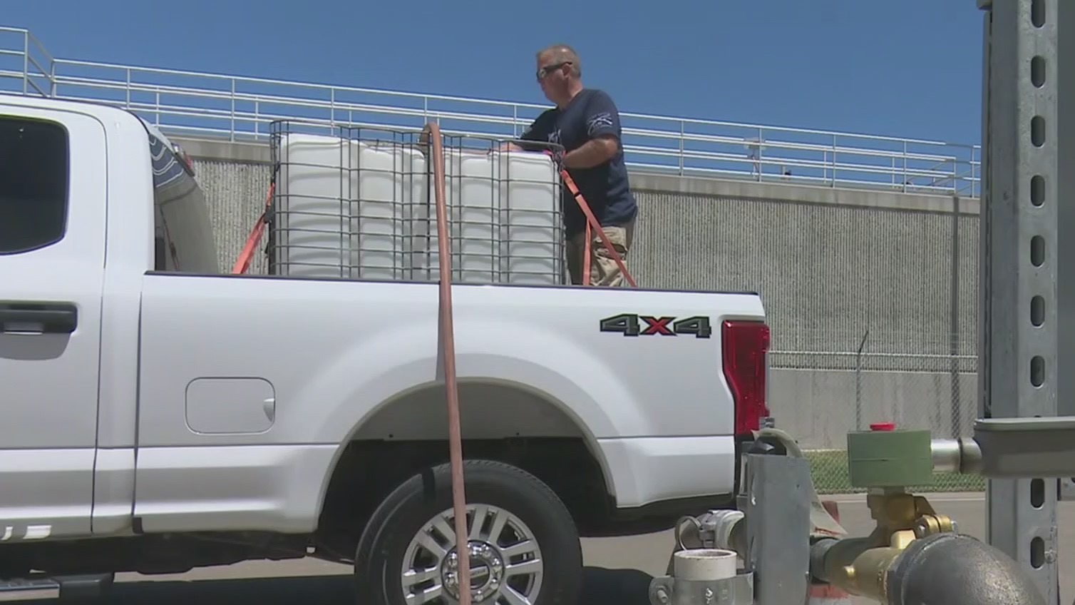 A Brentwood resident fills a water tank placed in the back of his pickup with recycled water. (CBS)